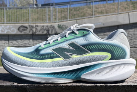 New Balance Ellipse review: running shoe in blue-teal gradient with neon-yellow accent, placed on a wooden railing outdoors.