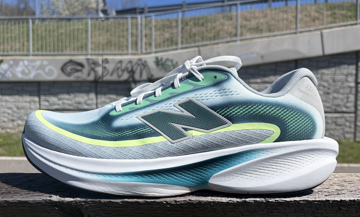 New Balance Ellipse review: running shoe in blue-teal gradient with neon-yellow accent, placed on a wooden railing outdoors.